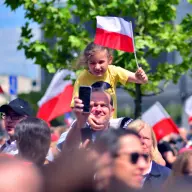 Dziewczynka machająca biało-czerwoną flagą w świątecznym tłumie