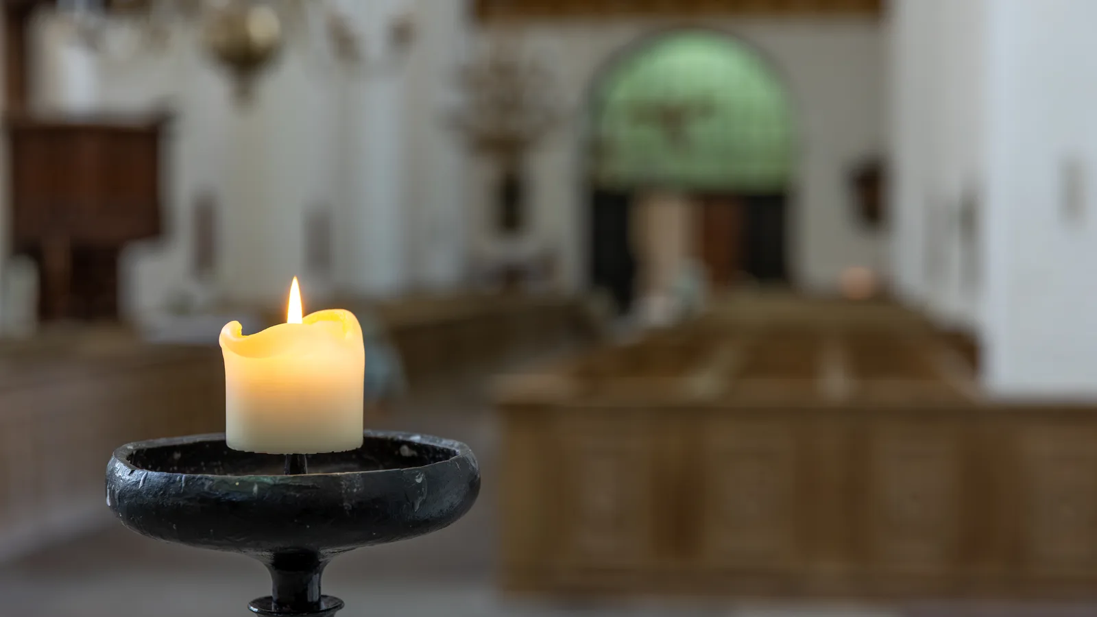 Zapalona świeca w kościelnym wnętrzu