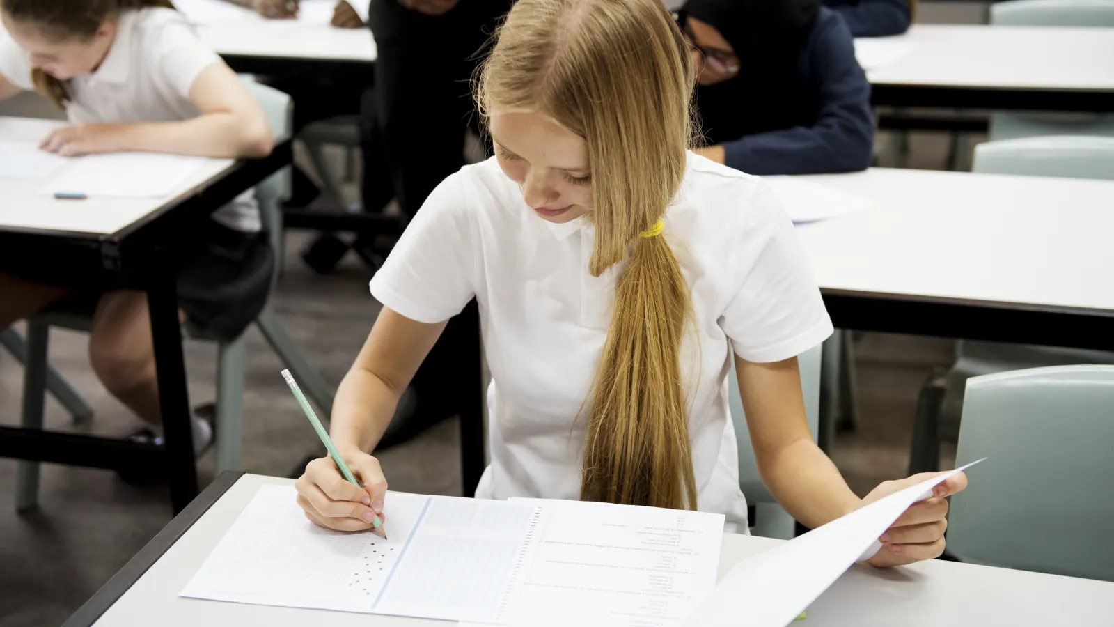 Maturzystka pisząca egzamin przy osobnym stoliku w sali egzaminacyjnej
