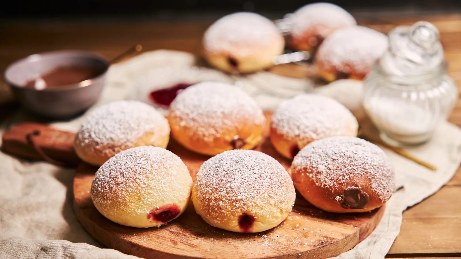 Pączki z nadzieniem posypane cukrem pudrem na drewnianej desce